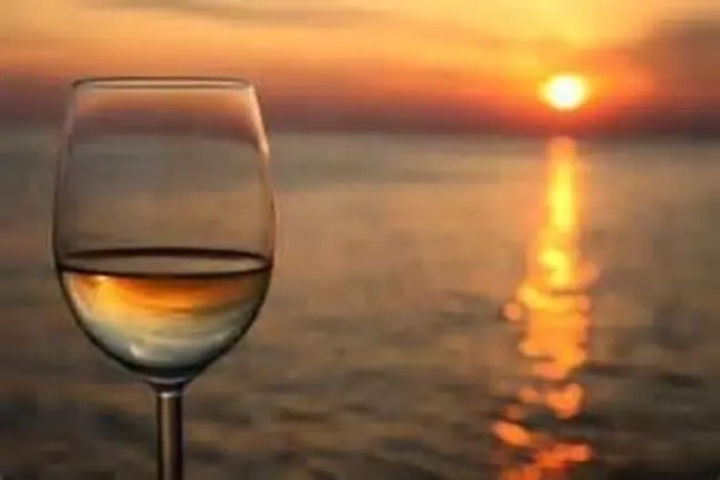 Wine glass with sunset over the ocean in the background.